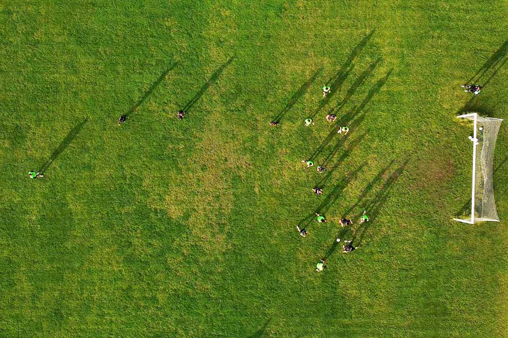An aerial view of a group of people playing soccer outdoors. An aerial view of a group of people playing soccer outdoors.