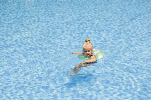 A young girl floating in an inner tube in a swimming pool.
