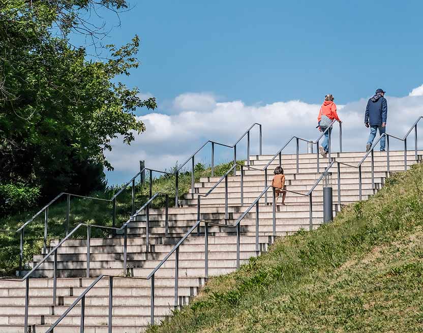 Two adults and a young child walking up a flight of stairs at a park. Two adults and a young child walking up a flight of stairs at a park.