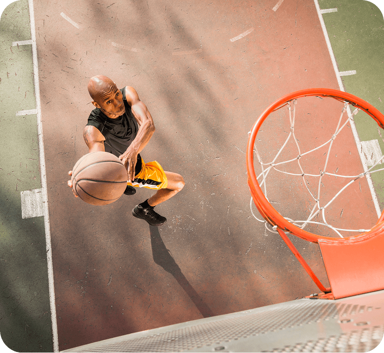 Un homme joue au basketball à l’extérieur.
