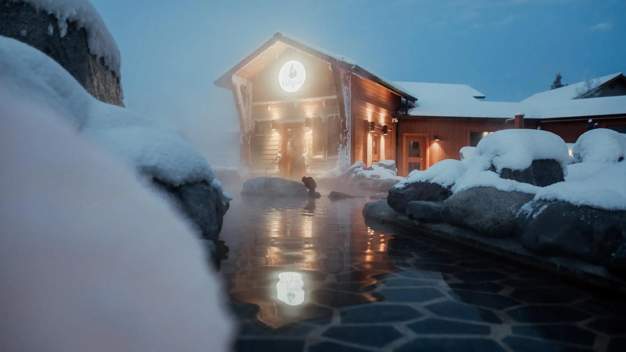 Un bain thermal extérieur devant un pavillon couvert de neige. Un bain thermal extérieur devant un pavillon couvert de neige.
