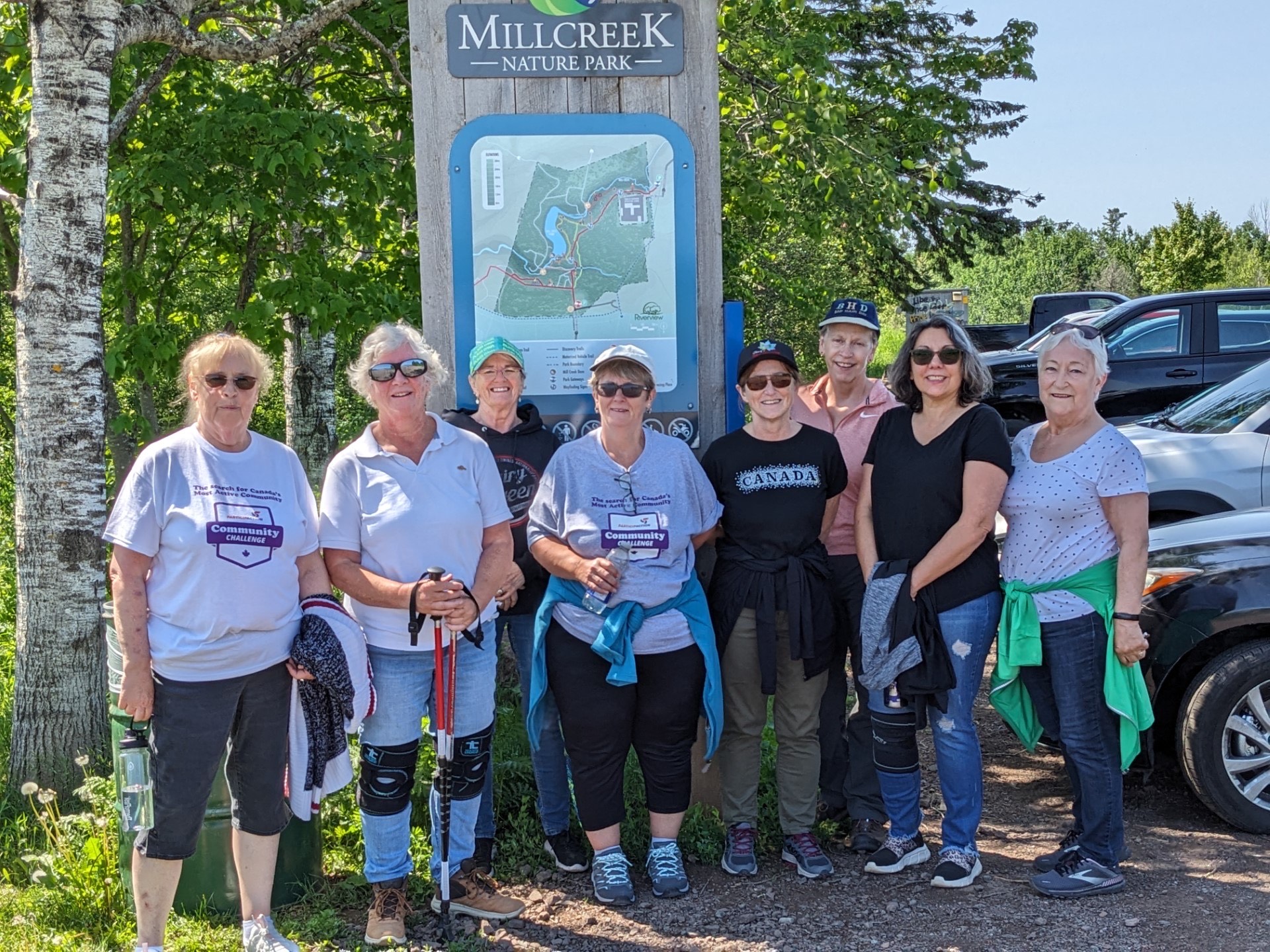 Residents of Salisbury, New Brunswick standing in a park parking lot. Residents of Red Deer, Alberta standing on a field in front of a billboard.