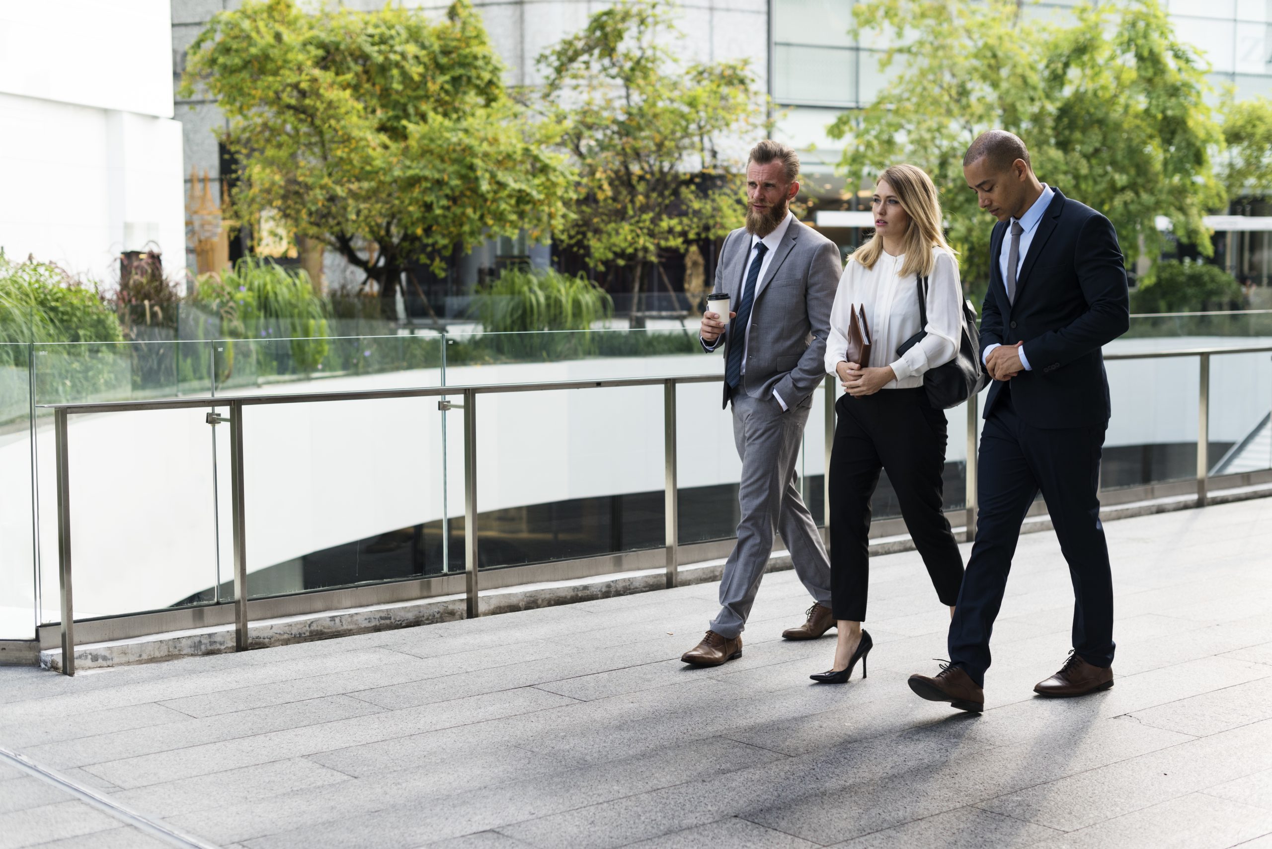 A group of people in business clothes walking on the sidewalk. 