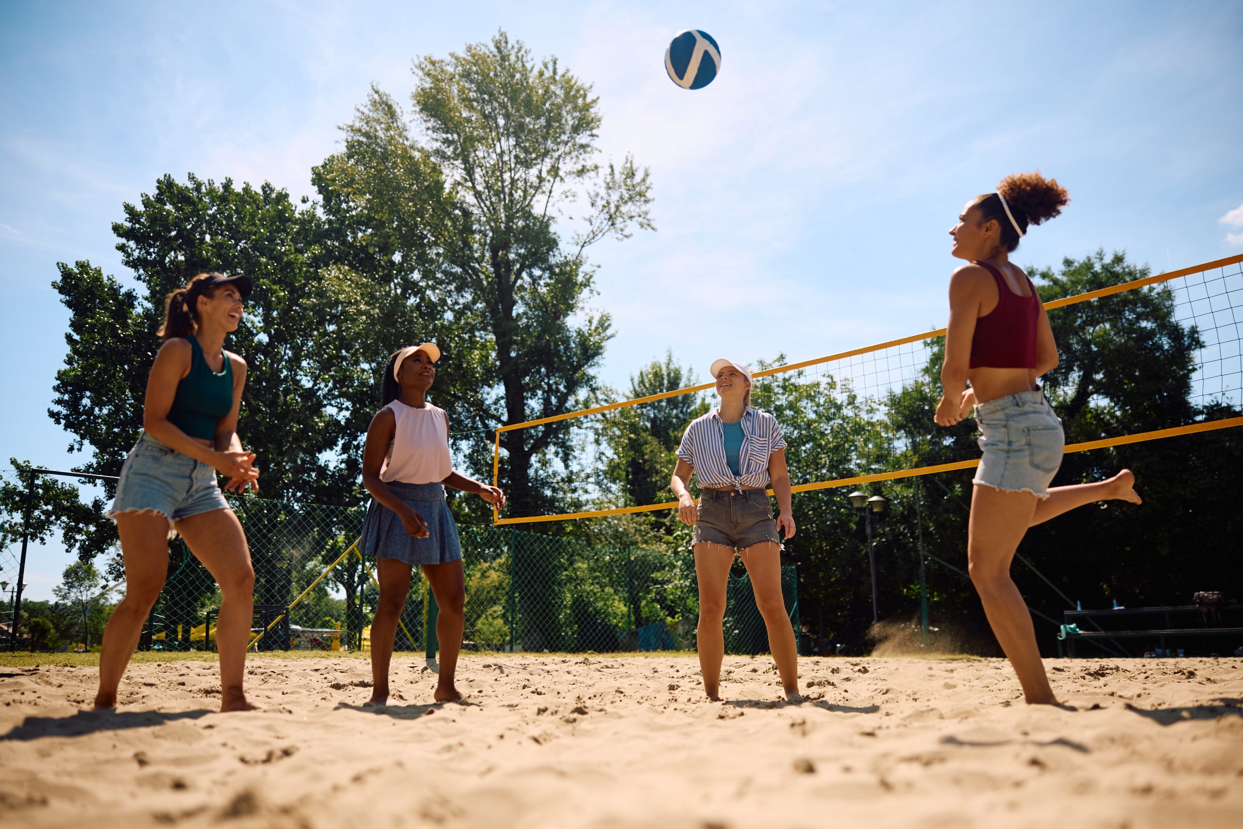 A group of women playing outdoor beach volleyball. 
