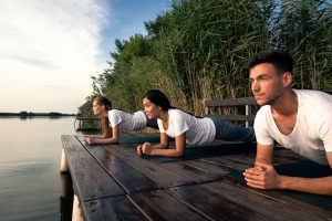 A group of people doing the plank exercise on a dock.