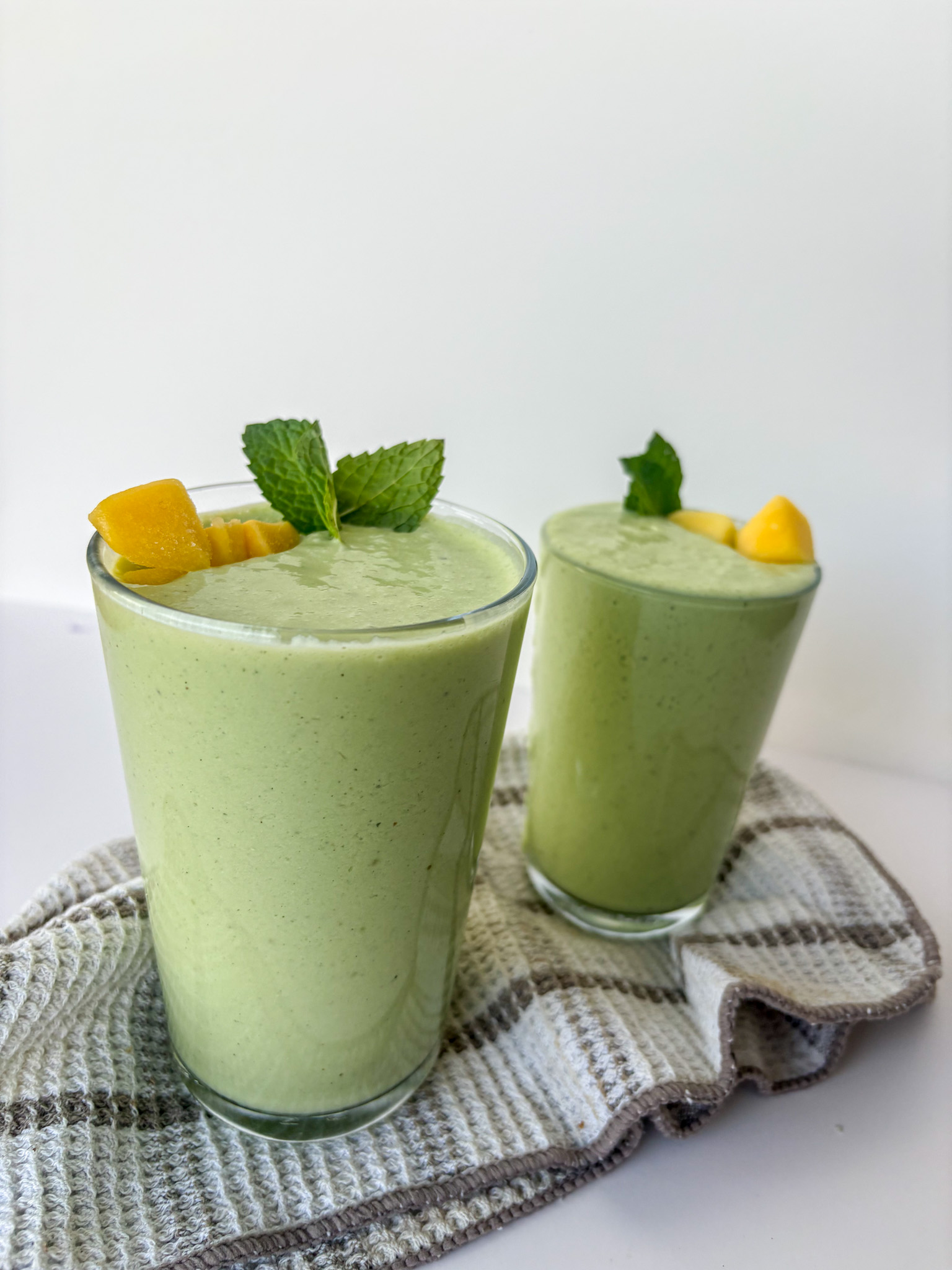 Two green smoothies on a counter. Fuel your movement recipe of the month: Tropical mango-coconut protein smoothie