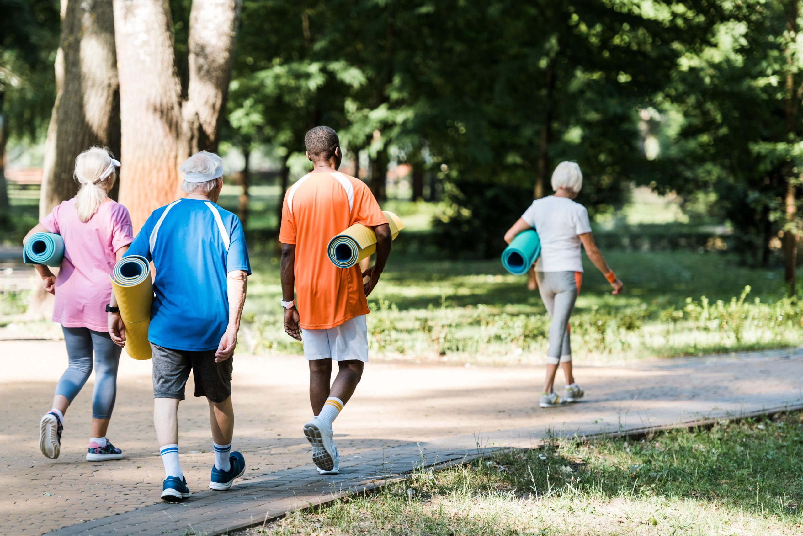 A group of older adults holding yoga mats while walking on a park path. How to exercise with arthritis and maximize the benefits of physical activity: 10 tips from an exercise specialist