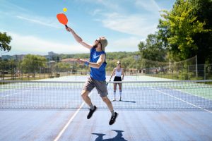 Deux personnes jouent au pickleball à l’extérieur.