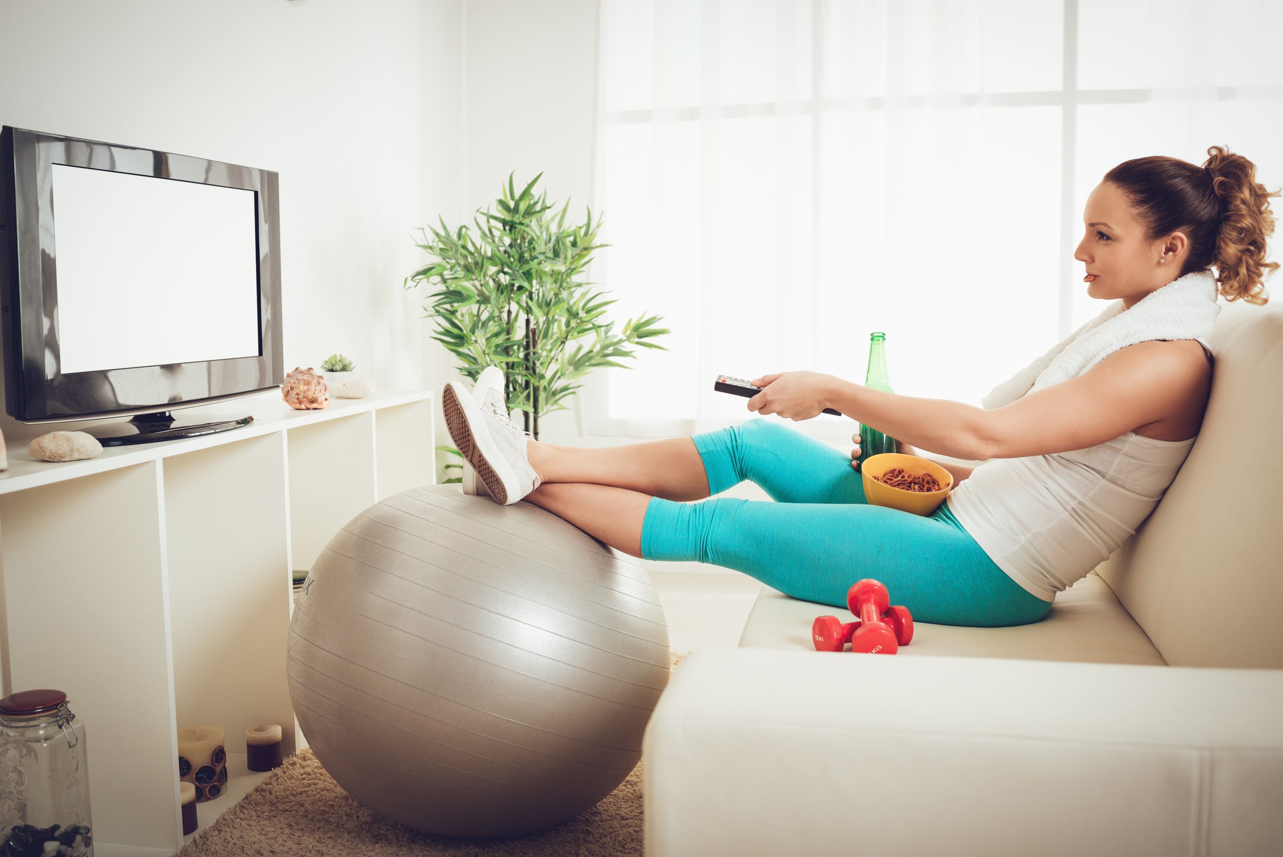 A woman in workout clothes watching TV.