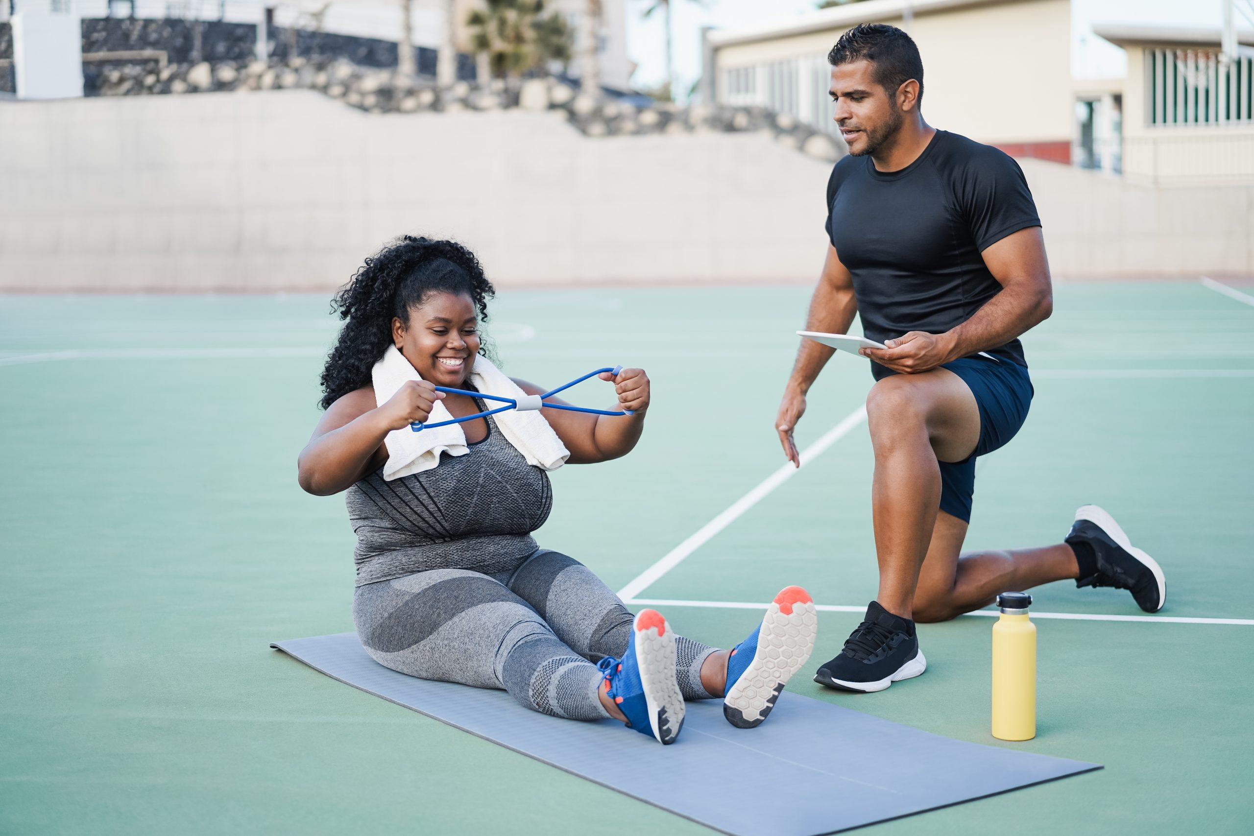 A personal trainer training his client on using a resistance band.   