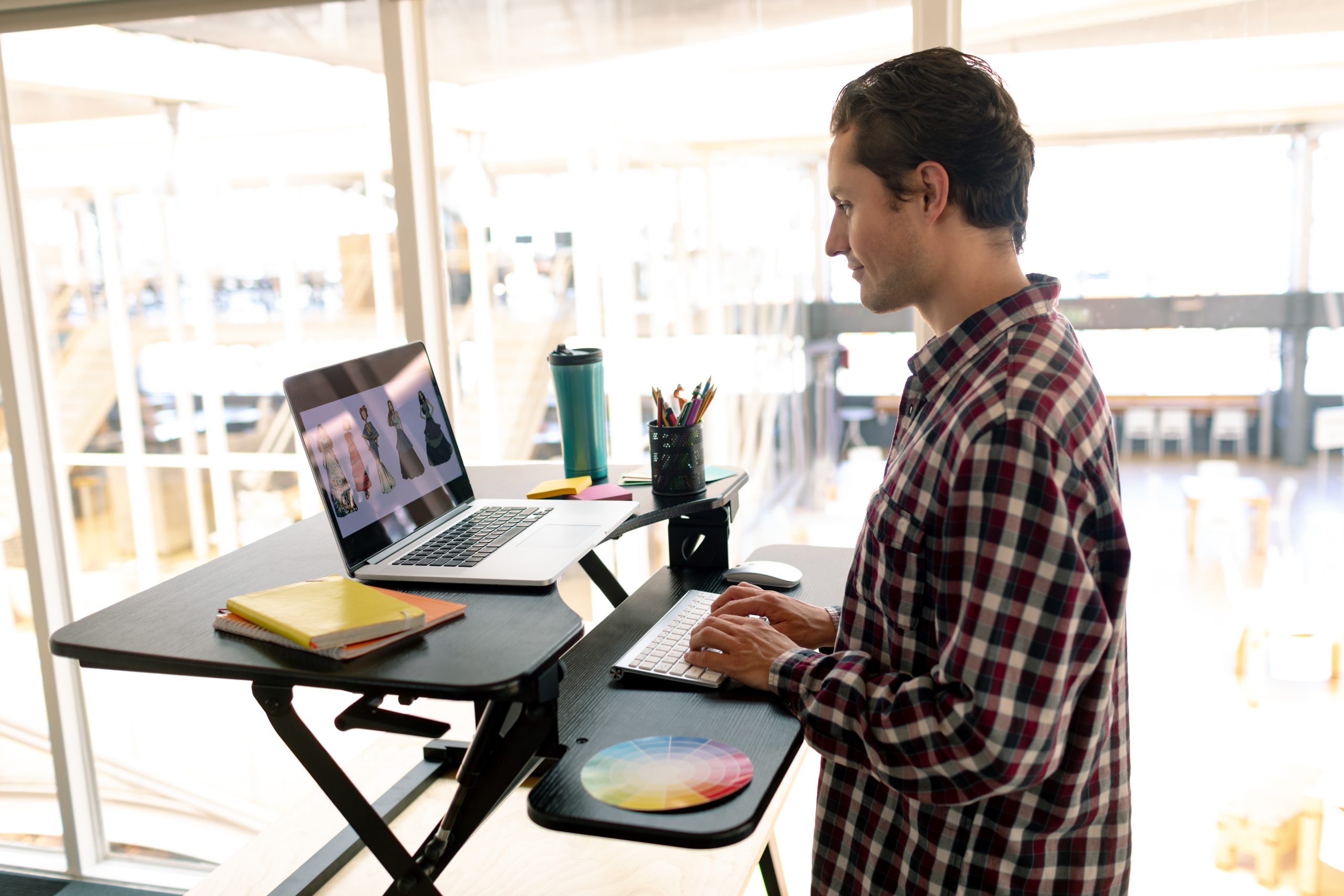 A man working on a computer on an adjustable standing desk.  