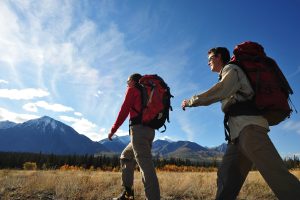 Deux personnes en randonnée dans un champ entouré de montagnes.